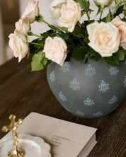 Marian Vase styled with roses, sitting on a brown wooden coffee table, next to the Catechism of the Catholic Church. 