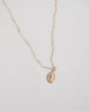 Gold miraculous medal necklace on a light gray background