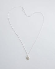 Silver miraculous medal necklace on a light gray background