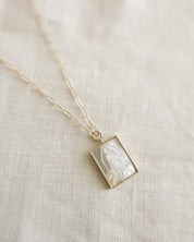 Necklace with a pearl our Lady of Guadalupe design on a beige fabric background