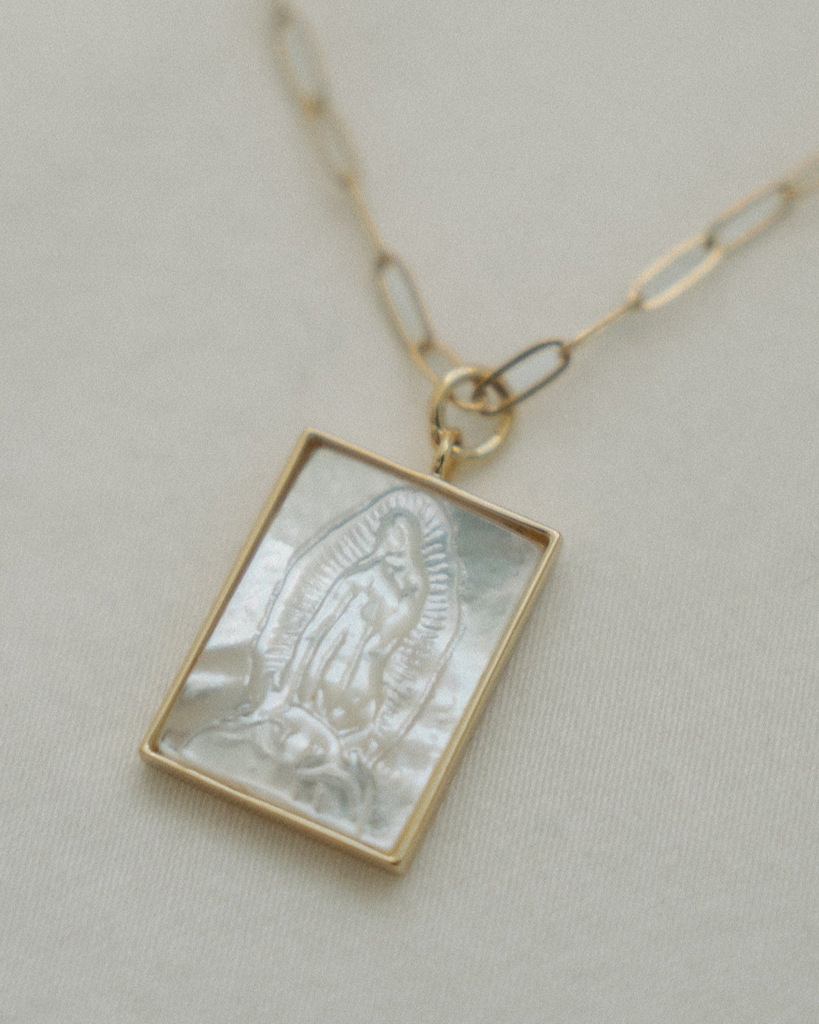 Necklace with a pearl rectangular Guadalupe pendant on a light background