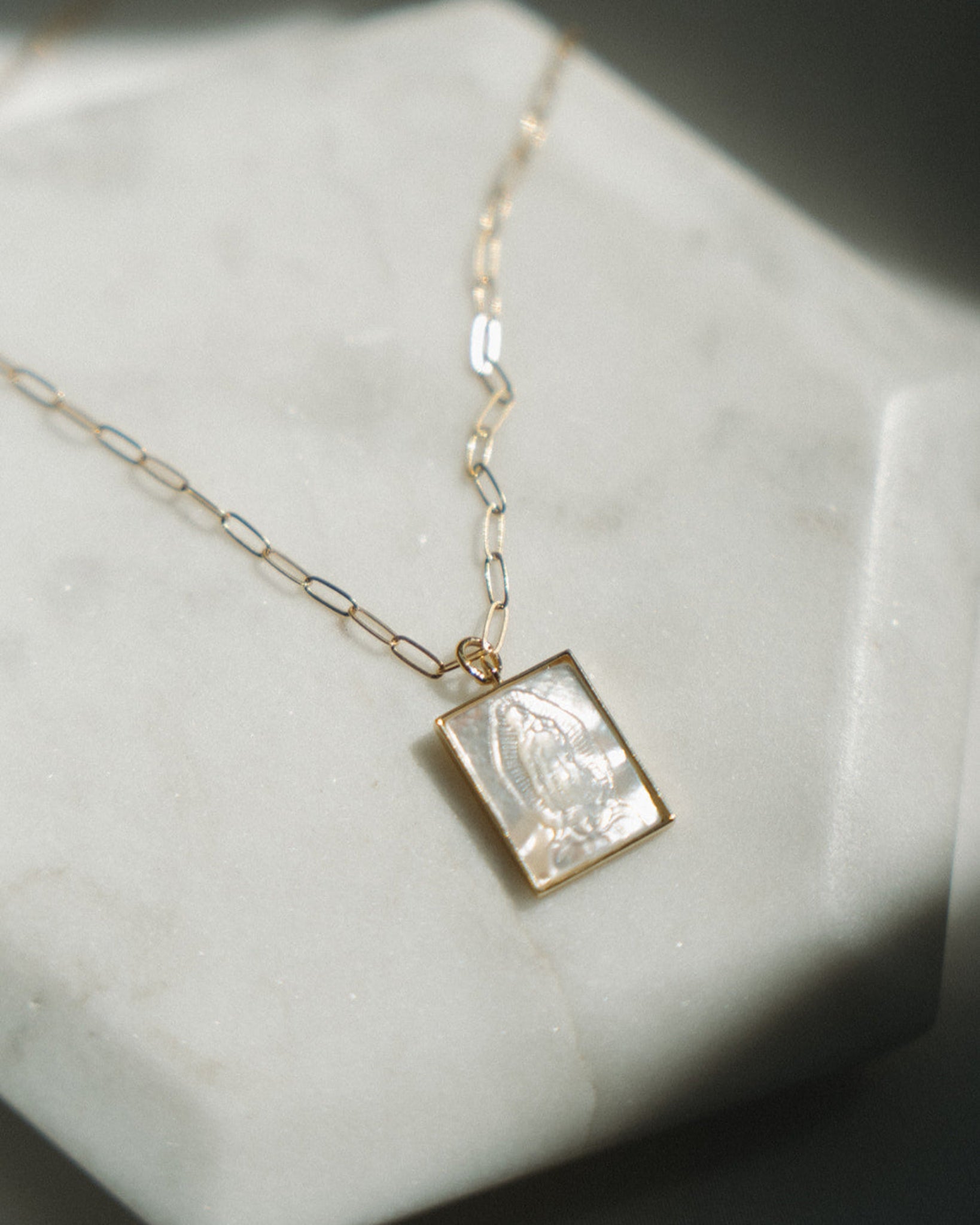 Gold pearl Guadalupe necklace with a paper clip chain on a light surface