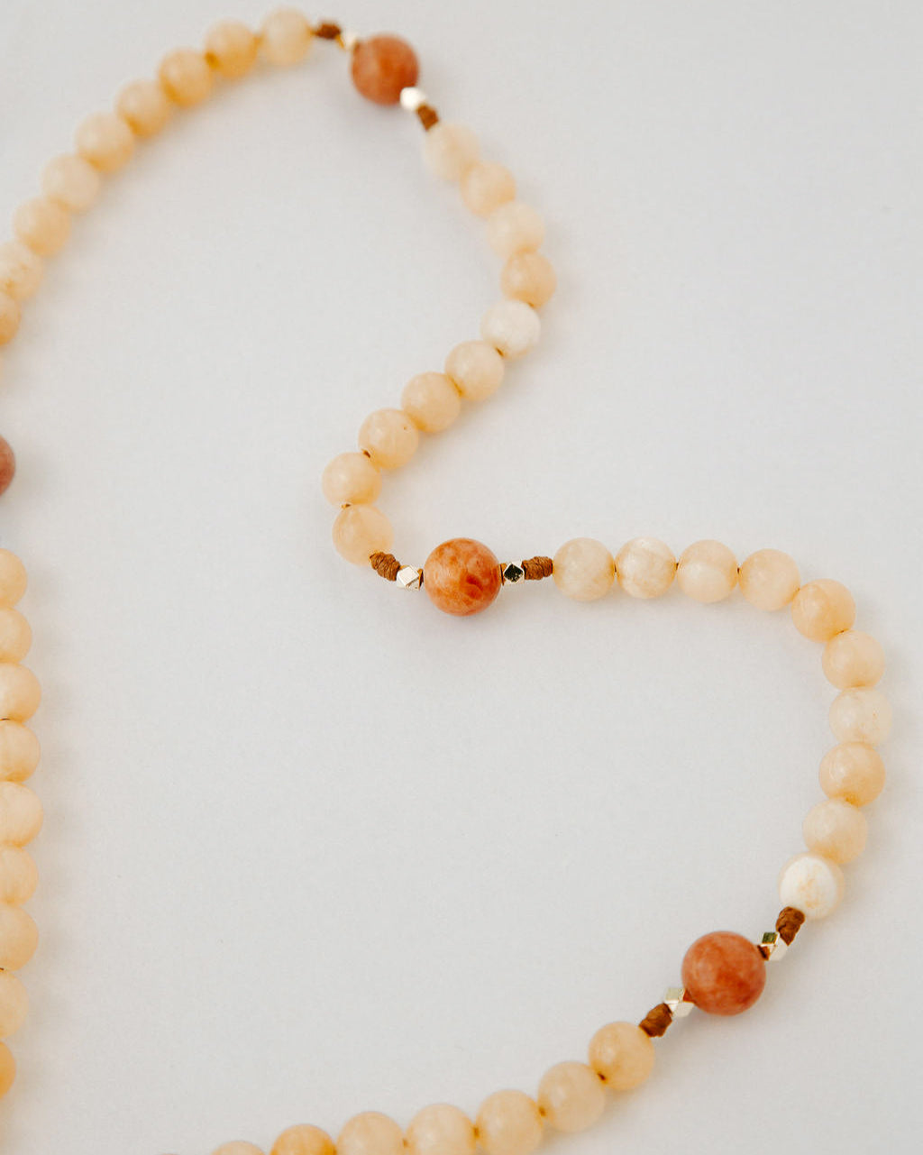 Rosary with cream and orange beads on a white background