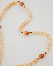 Rosary with cream and orange beads on a white background