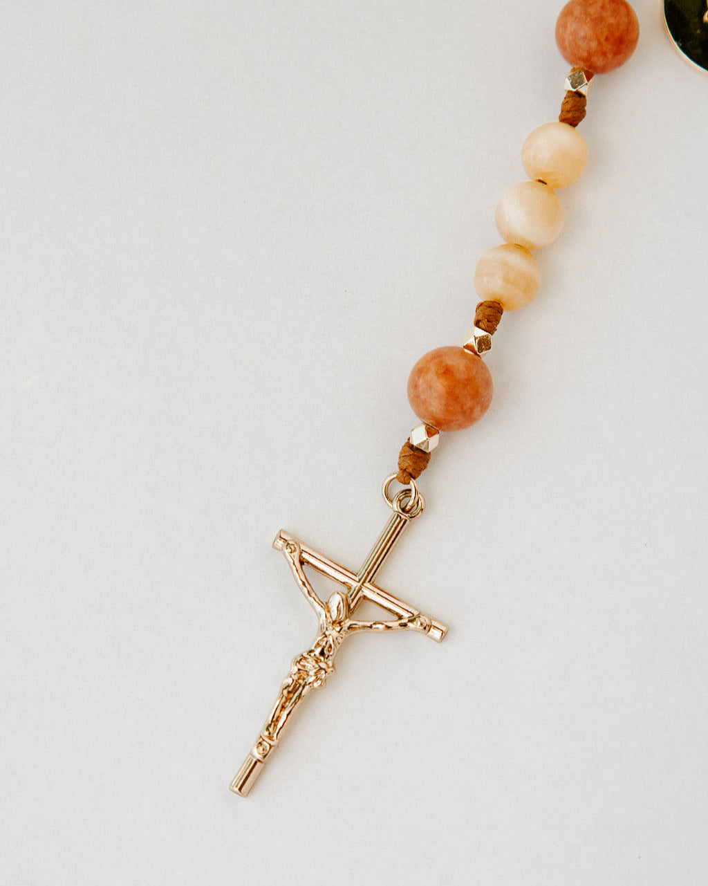 Rosary with cream and orange beads with gold cross on white background
