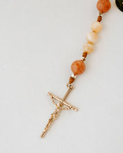 Rosary with cream and orange beads with gold cross on white background