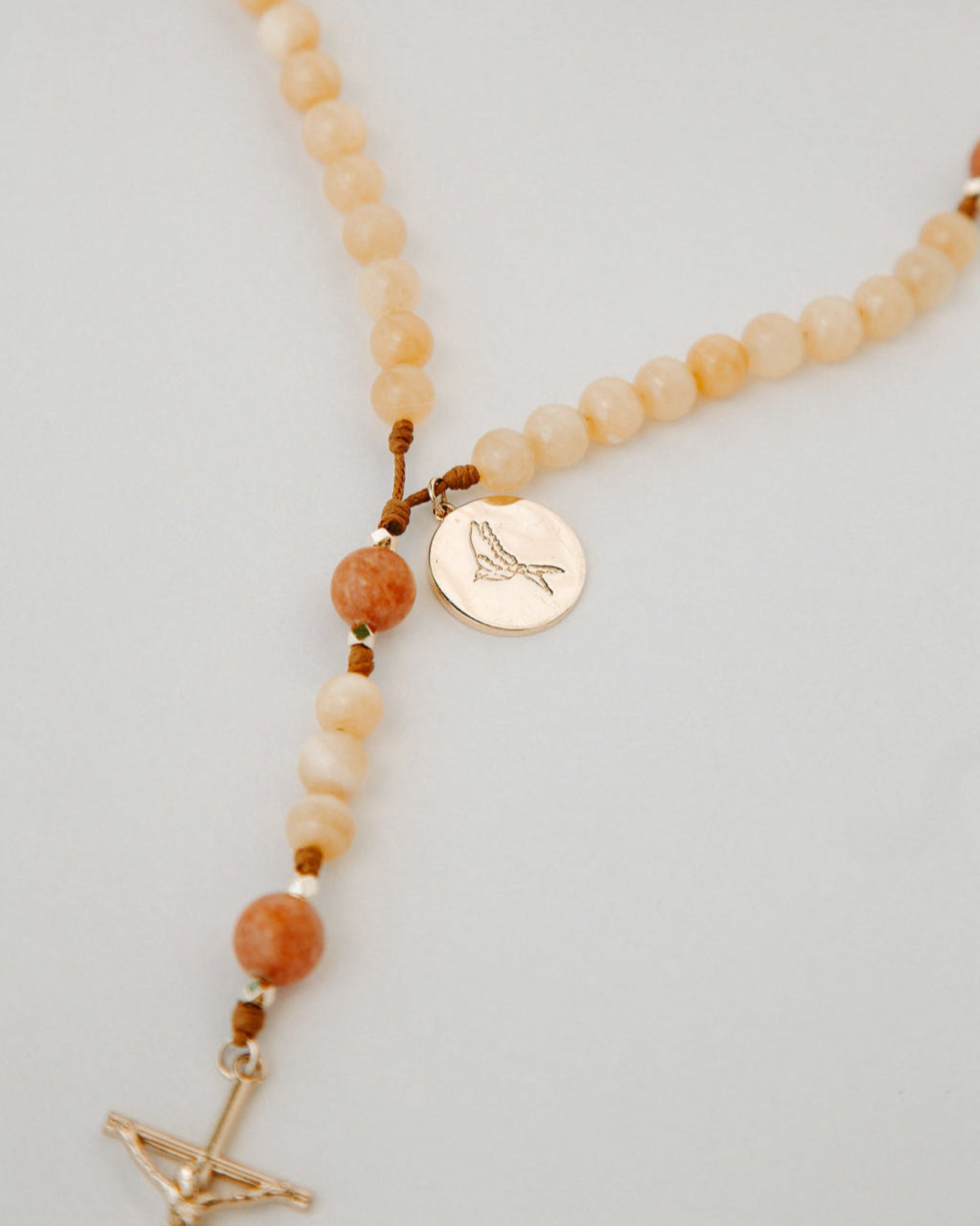 Rosary with cream and orange beads with gold medal on a white background