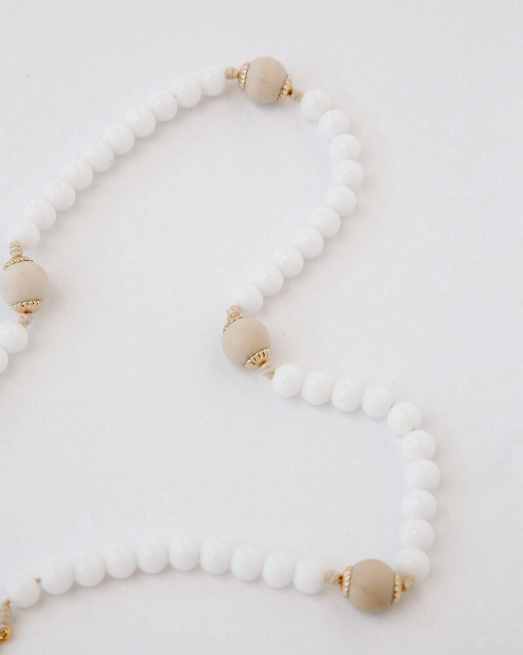 Rosary with white and beige beads on a light background