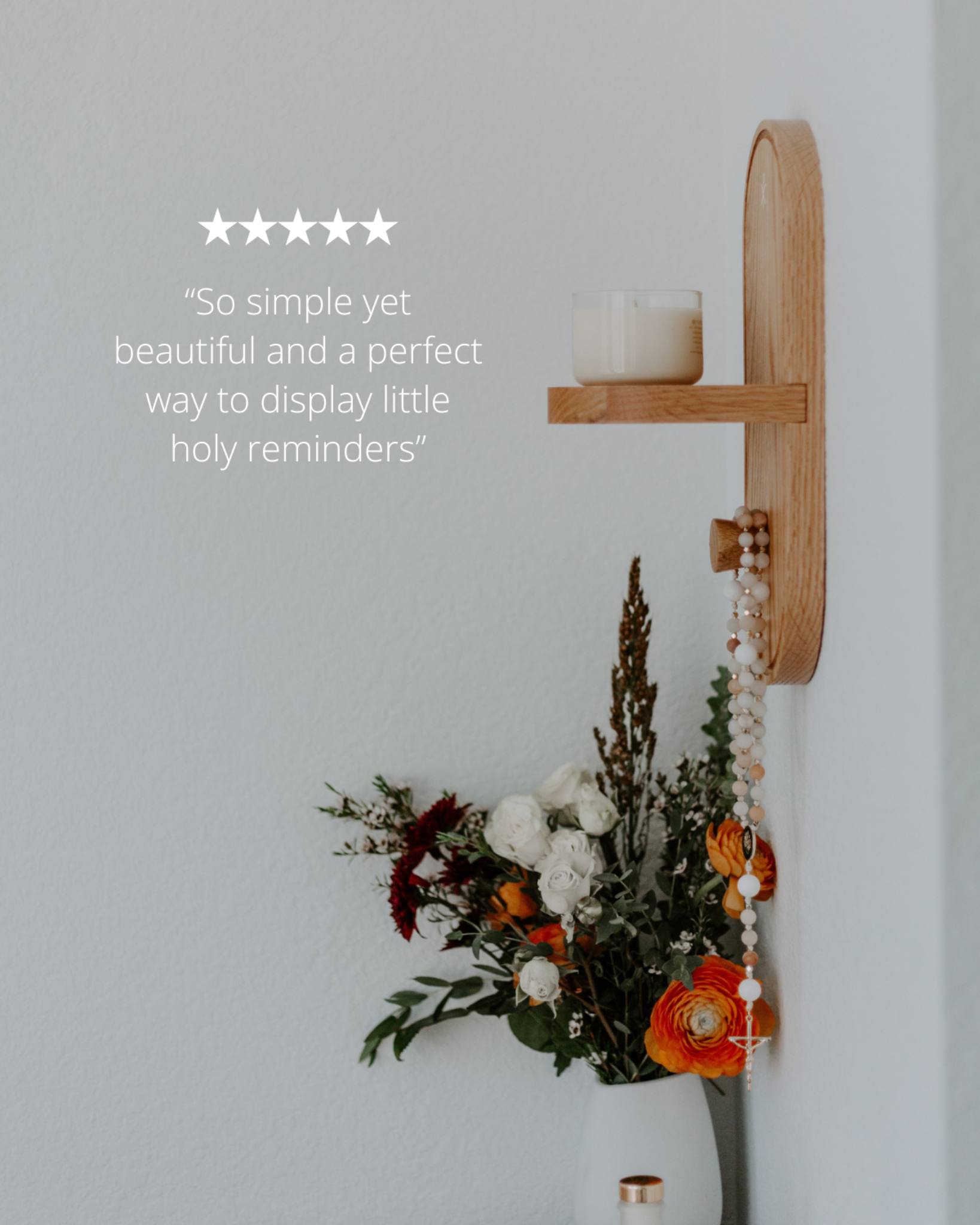 Wooden wall shelf with candle and floral arrangement against a light gray wall.