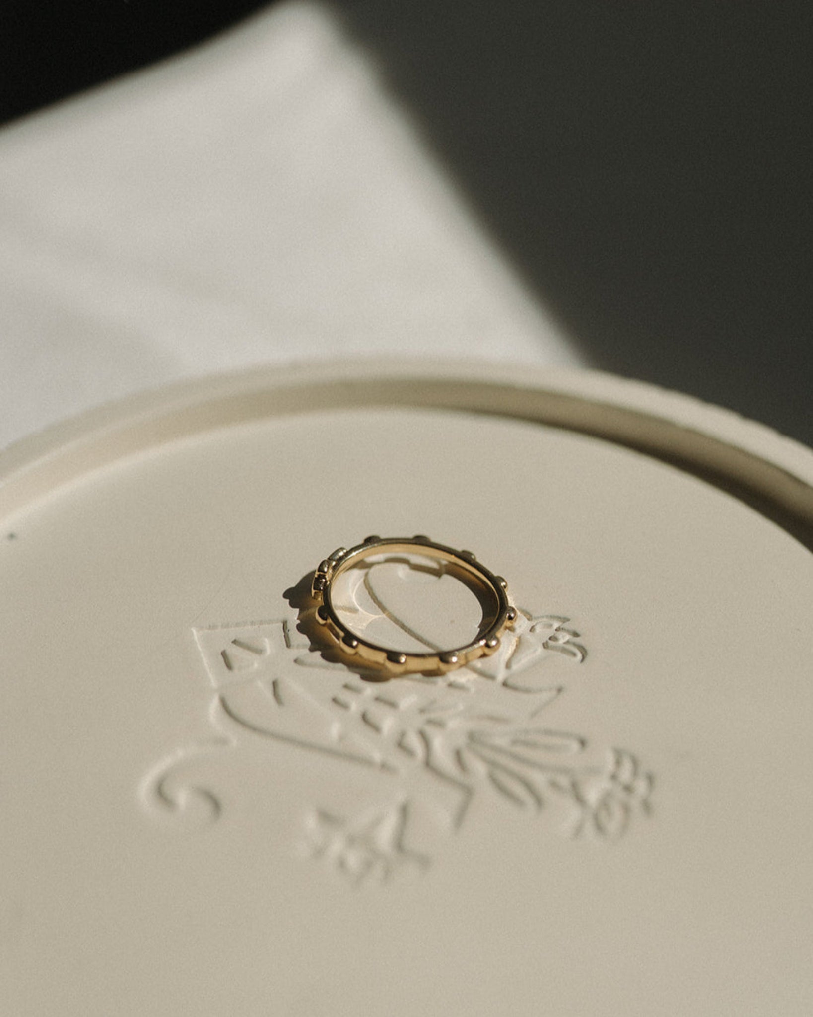 Gold rosary ring on a white surface with intricate designs