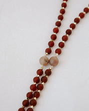 Beaded rosary with red and beige beads on a light gray background