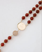 Beaded rosary with a gold medal on a light gray background