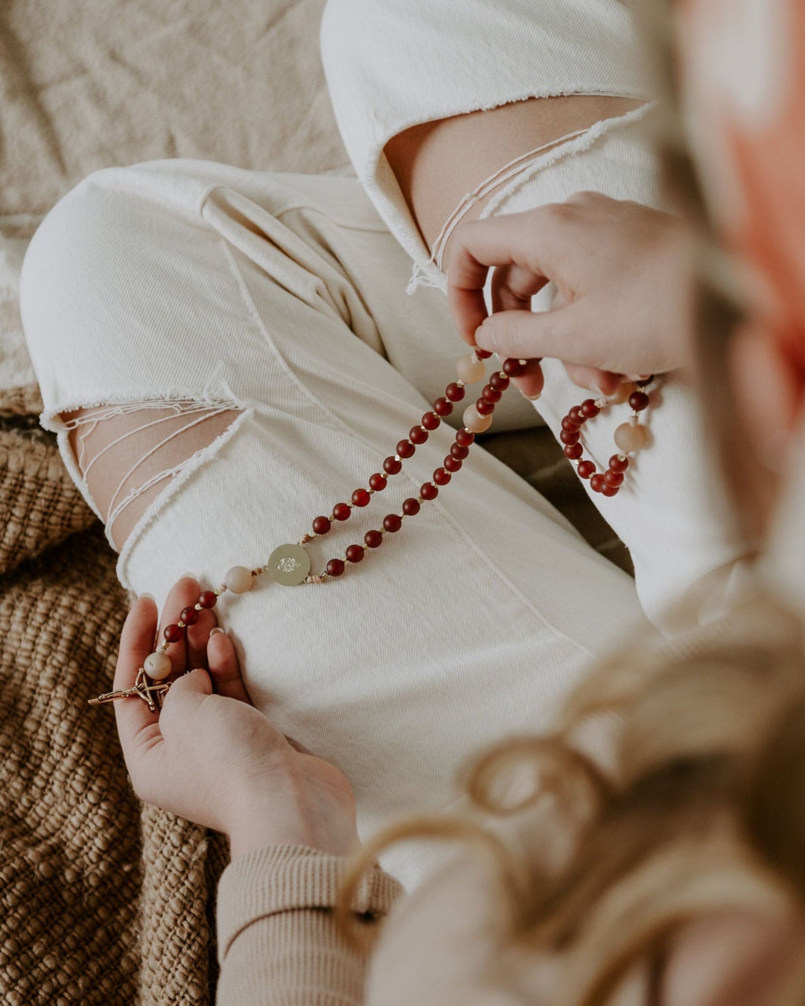 Person holding a rosary with a blurred background.