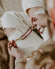 Person holding a rosary with a blurred background.