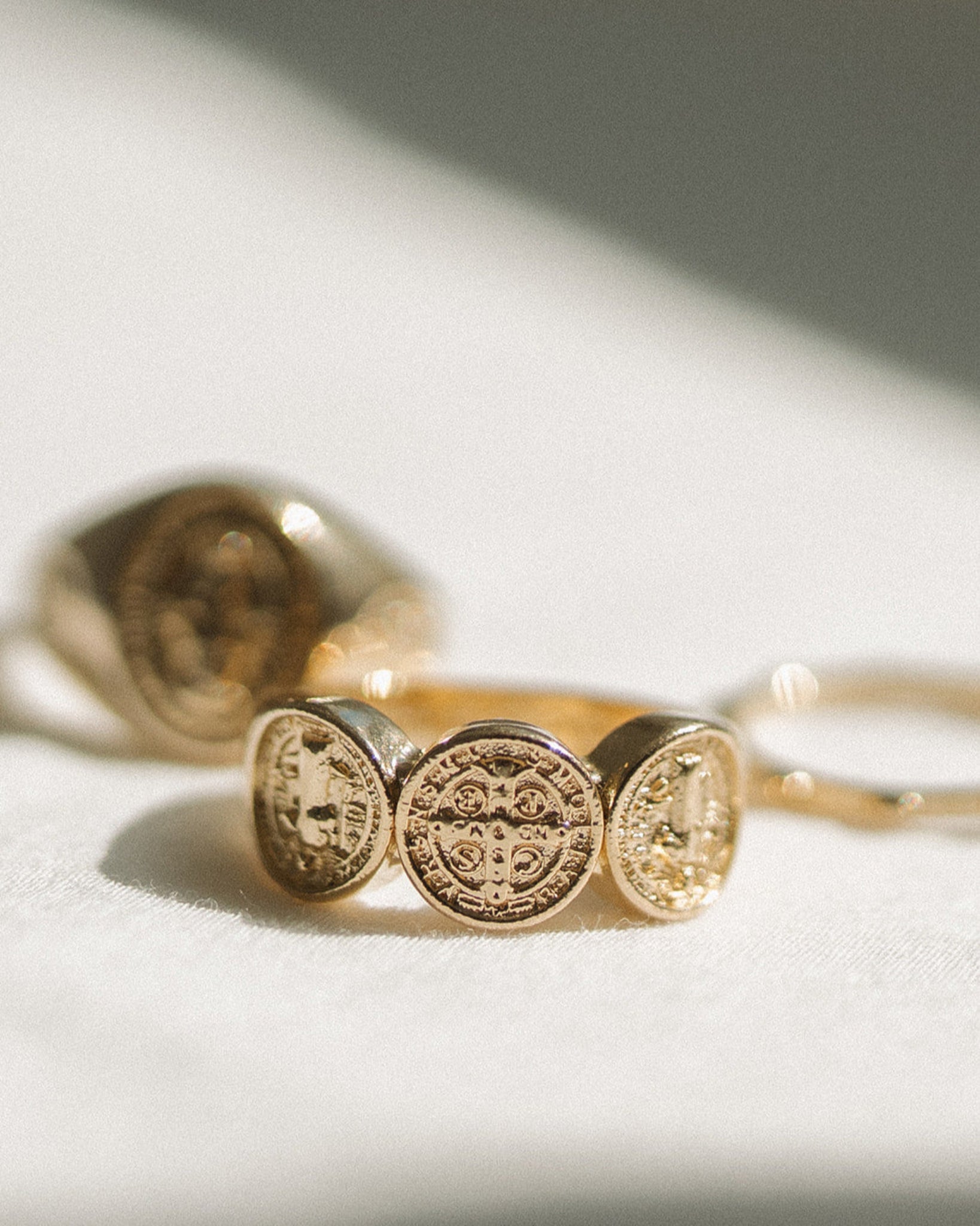 Gold St. Benedict ring on a light background