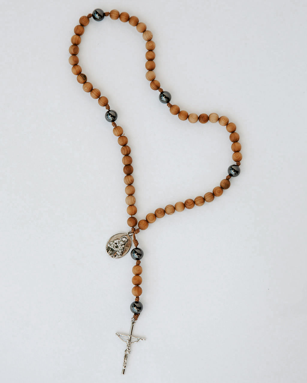Wooden rosary with black beads and a cross on a white background