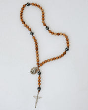 Wooden rosary with black beads and a cross on a white background