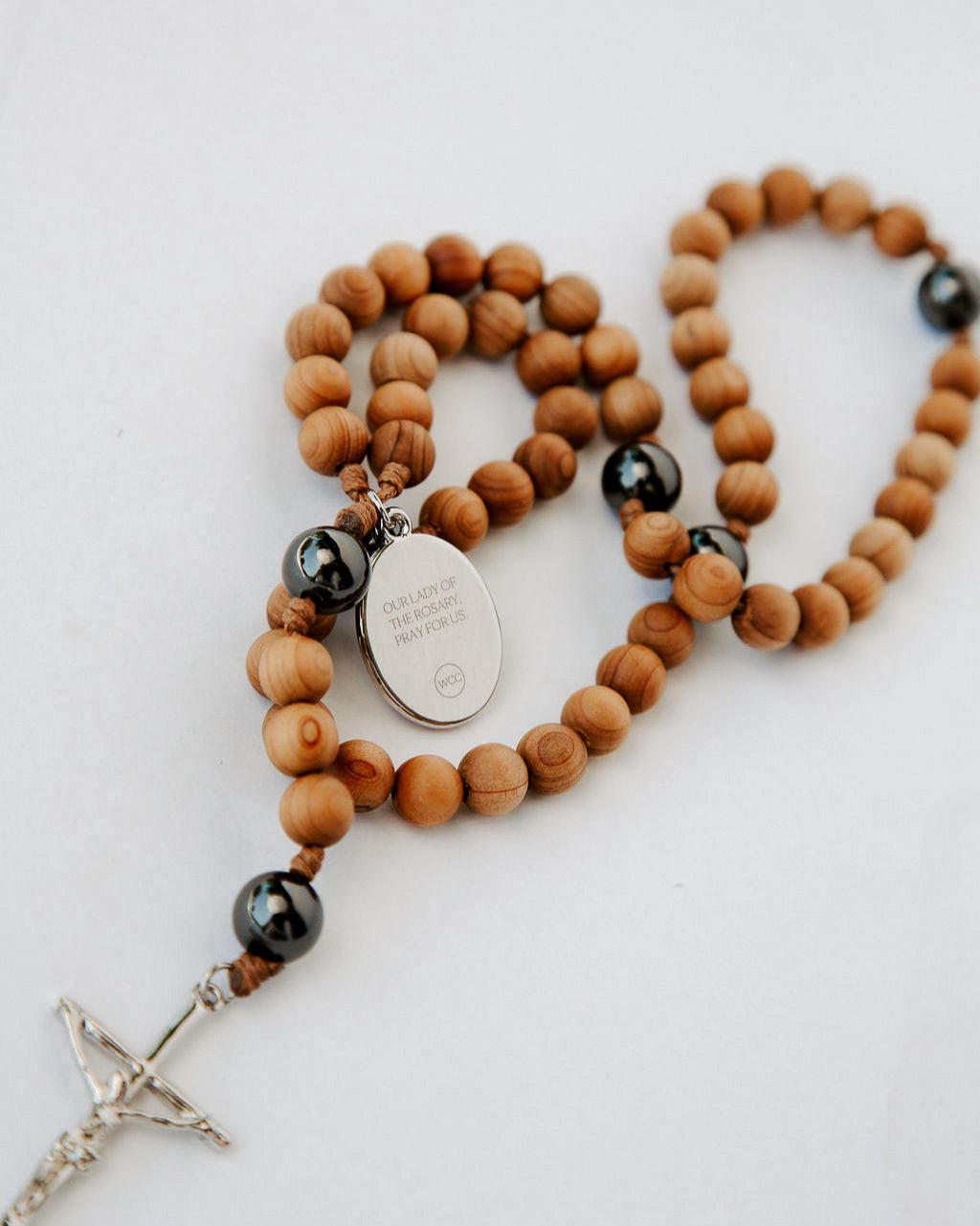 Wooden rosary with black beads and a silver cross on a white background