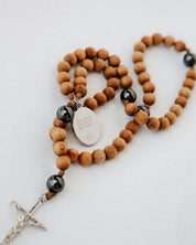 Wooden rosary with black beads and a silver cross on a white background