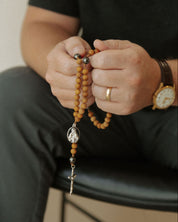 Person holding a rosary with a neutral background