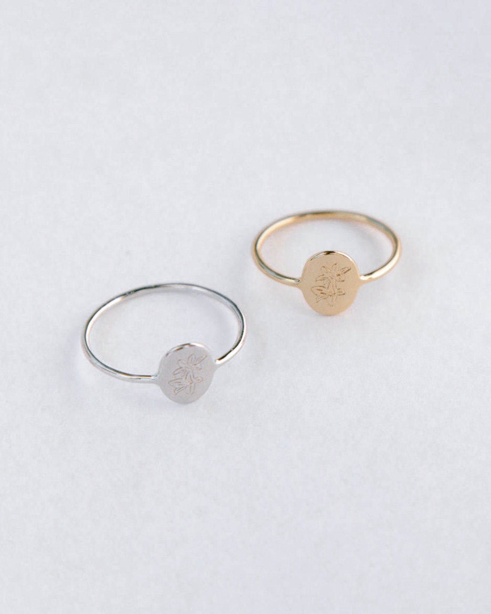 Two rings, one silver and one gold, on a light gray background