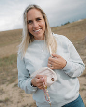Woman holding a pink cap and beads in a desert setting