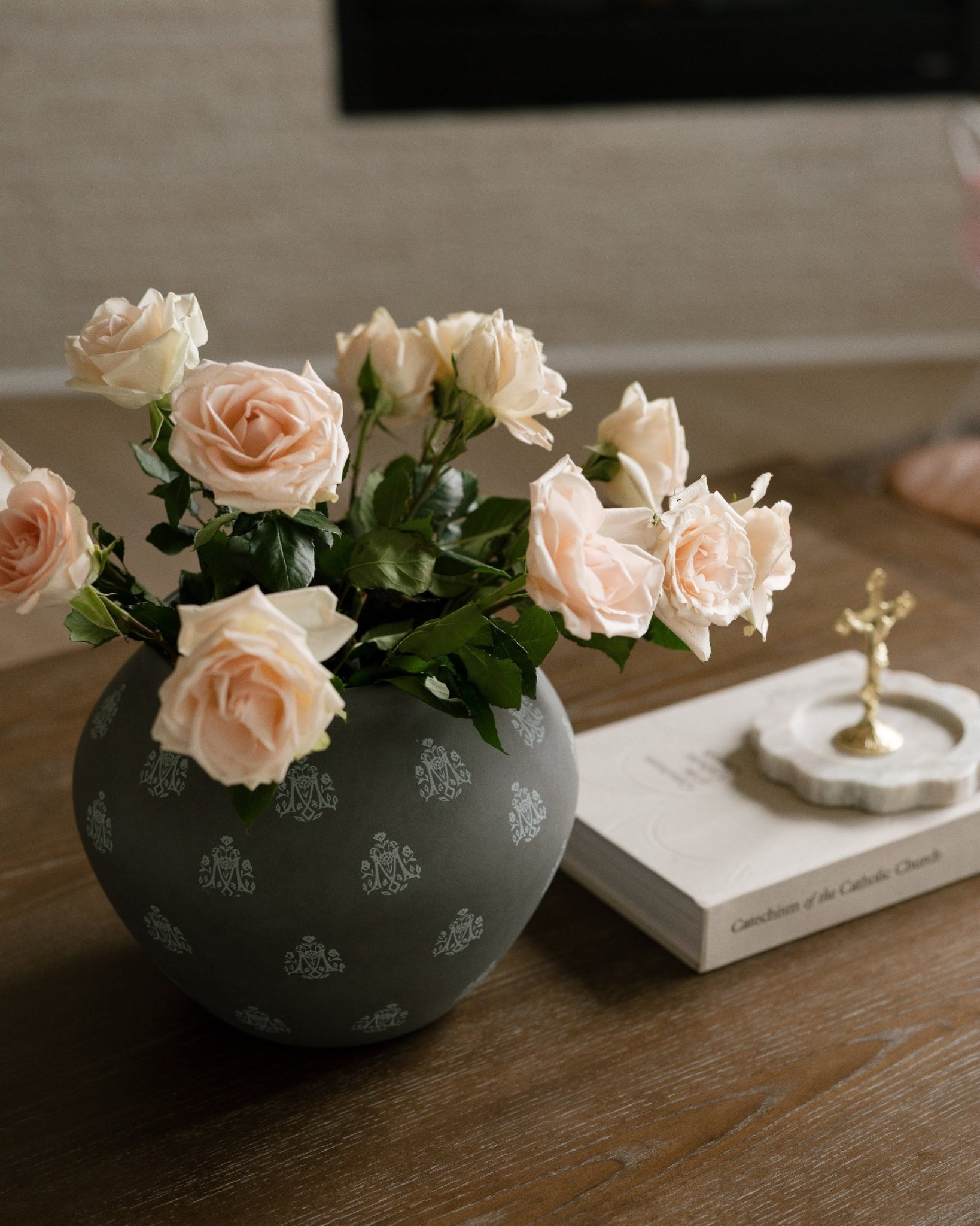 Styled Marian Vase in color umber. It is styled on a brown coffee table with pink roses, next to the Catechism of the Catholic Church. 