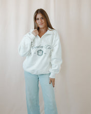 Woman wearing a white catholic sweatshirt with text and graphics, standing against a plain background