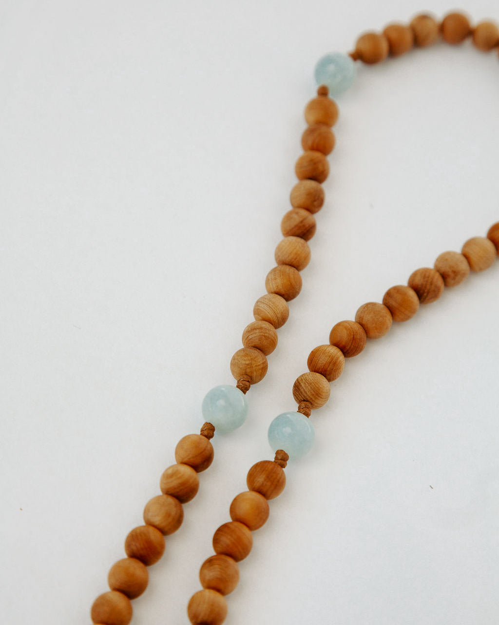 Wooden beaded rosary with light blue beads on a white background