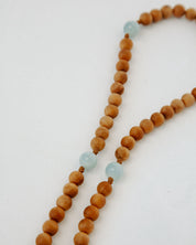 Wooden beaded rosary with light blue beads on a white background