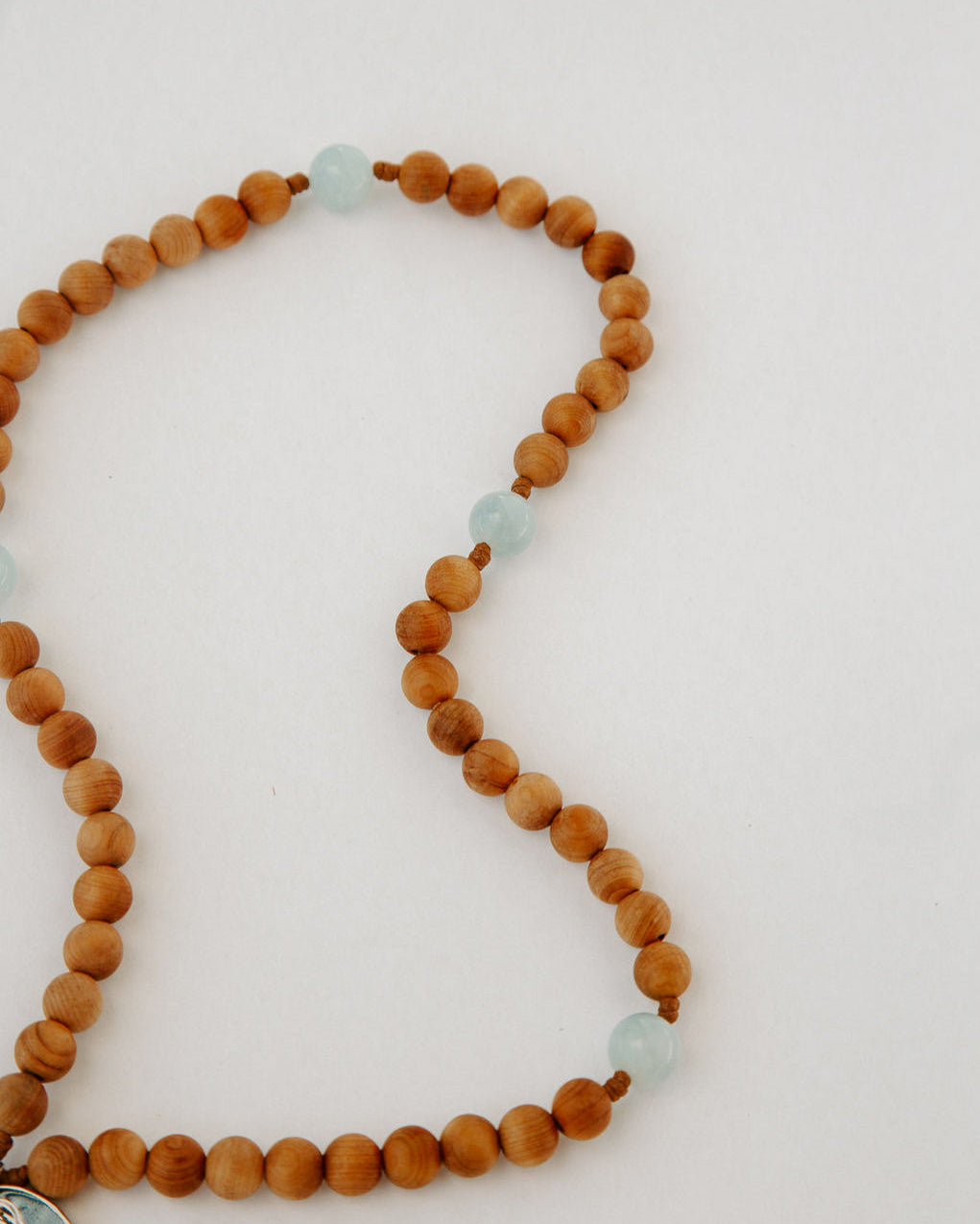 Rosary with wooden beads and light blue acers on a white background