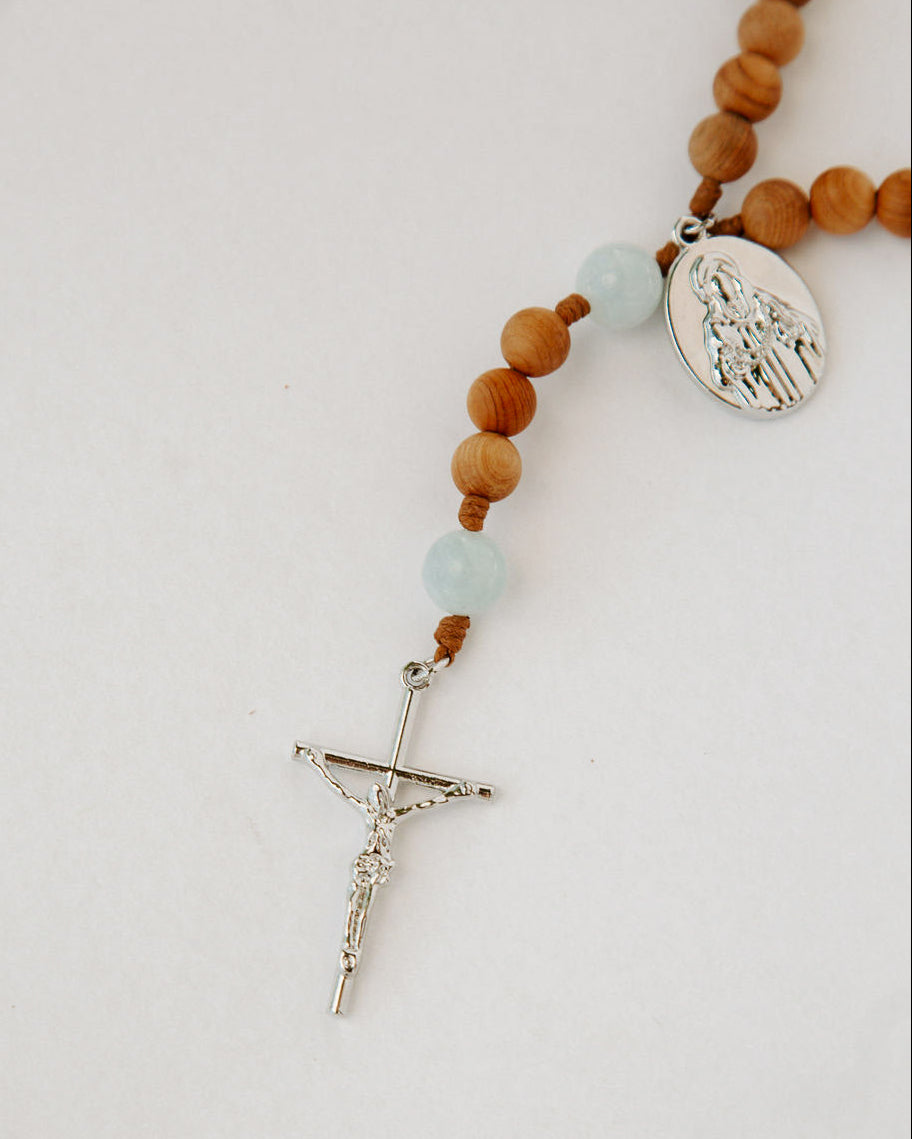 Rosary with wooden beads and a silver cross on a light background