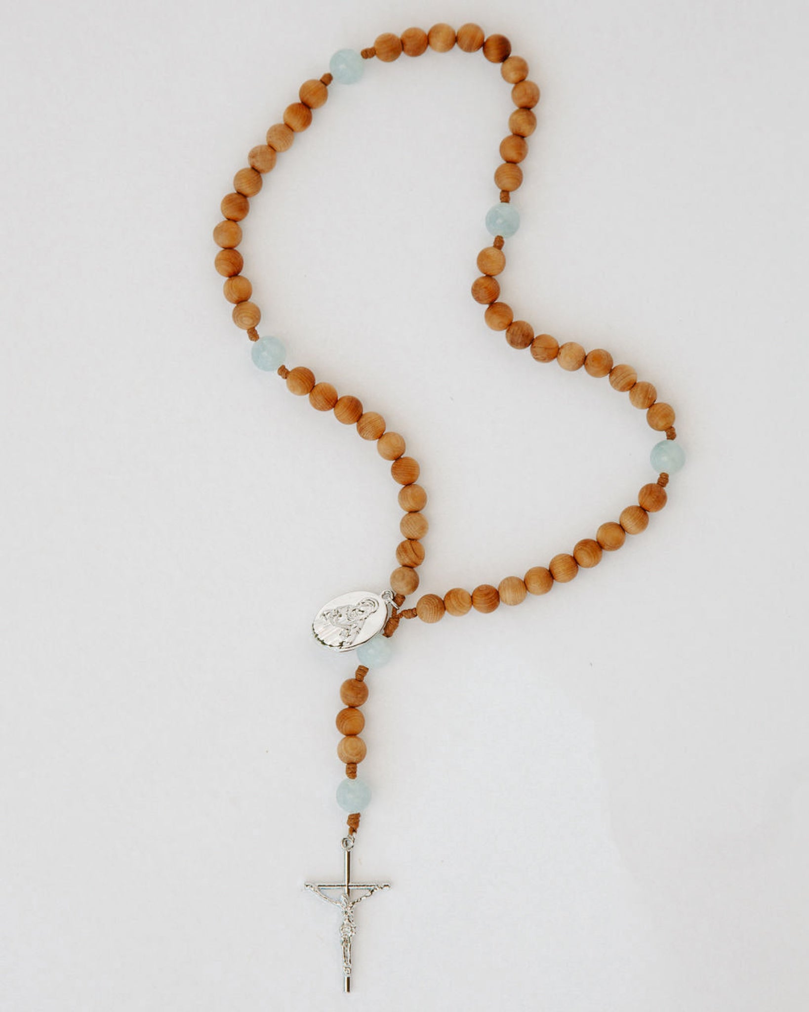 Wooden rosary with a cross on a light gray background