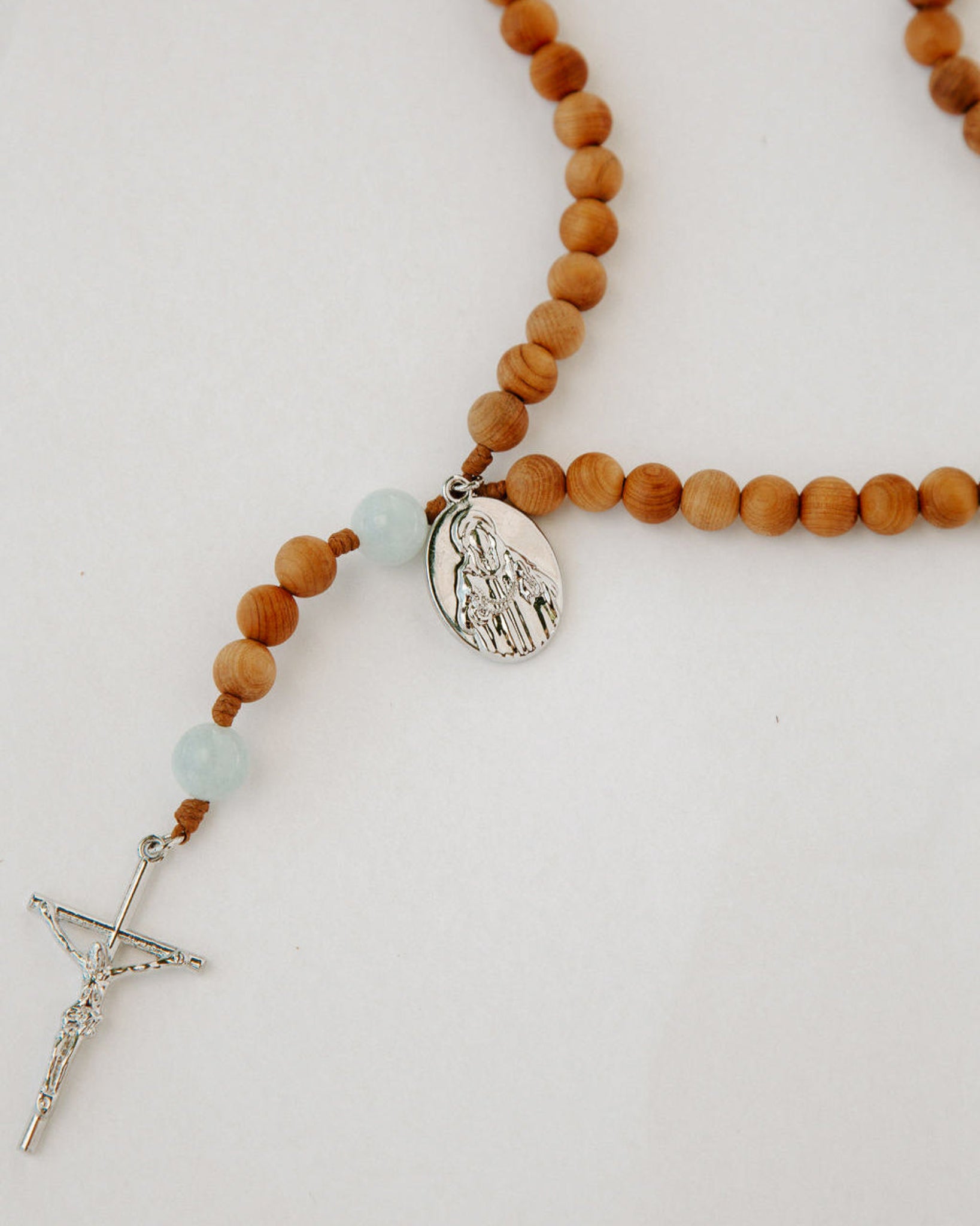 Wooden rosary with a silver cross and medal on a light background