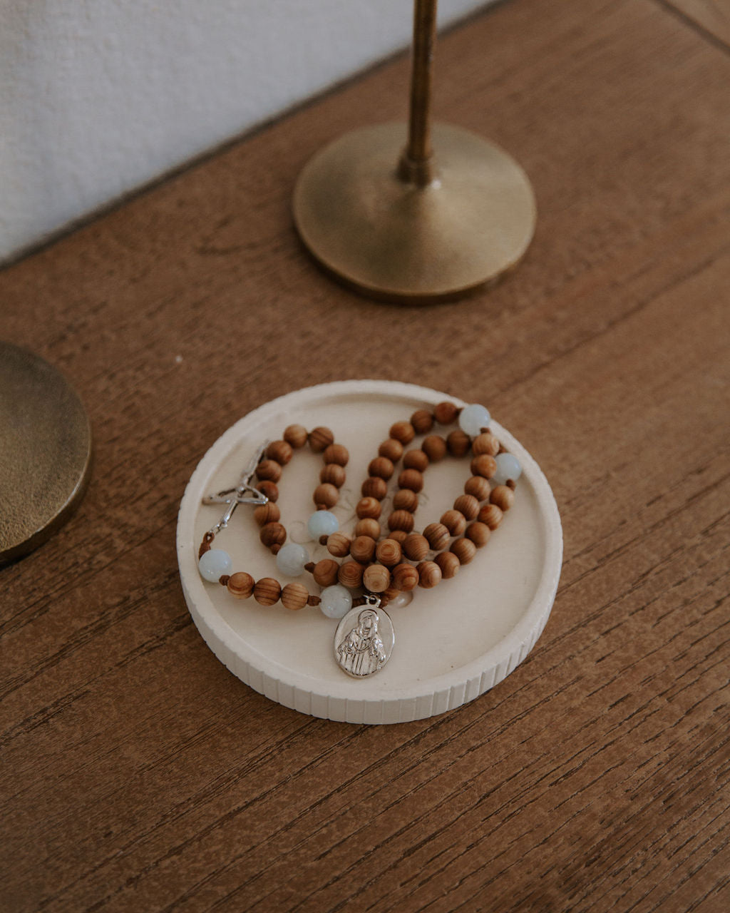 Wooden rosary in a ceramic dish on a wood table