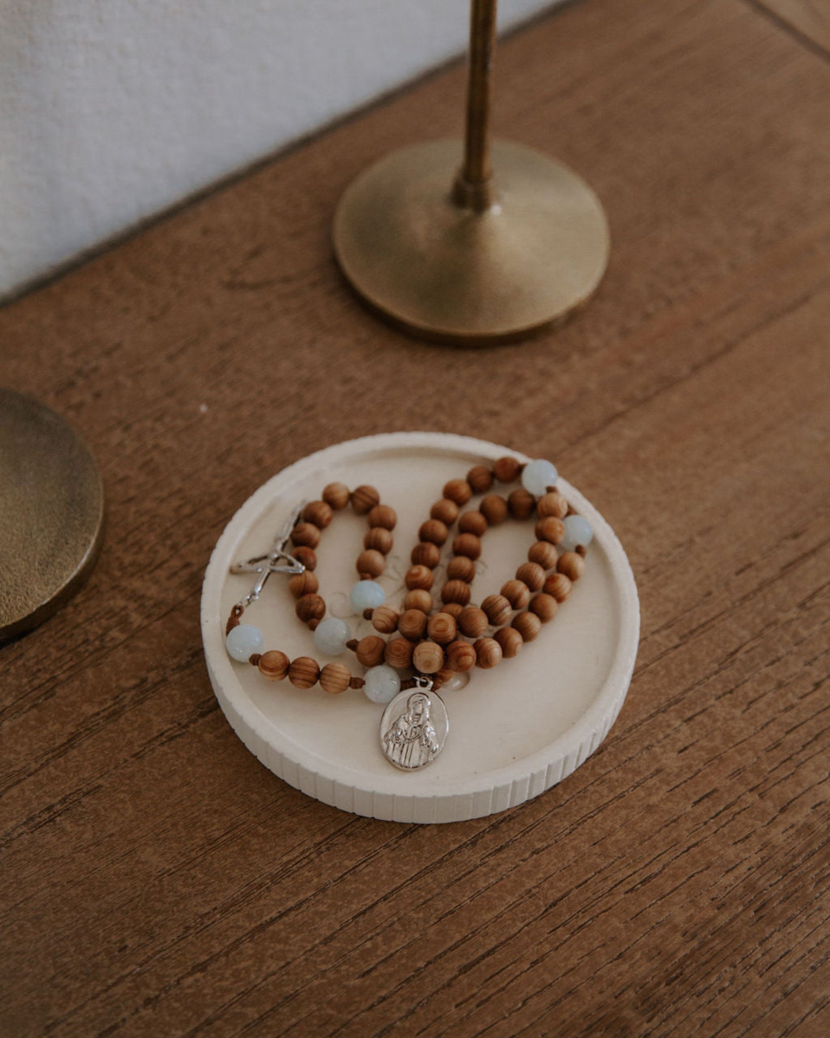 Wooden rosary in a ceramic dish on a wood table