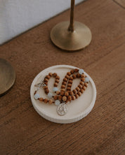 Wooden rosary in a ceramic dish on a wood table