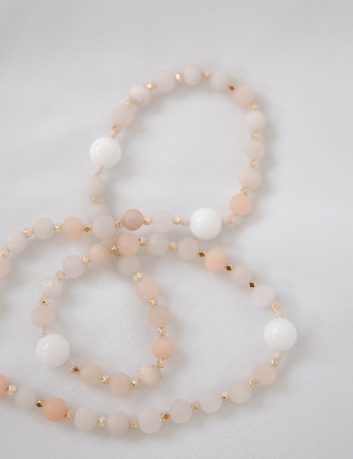 Pink and white immaculate heart rosary beads on white background