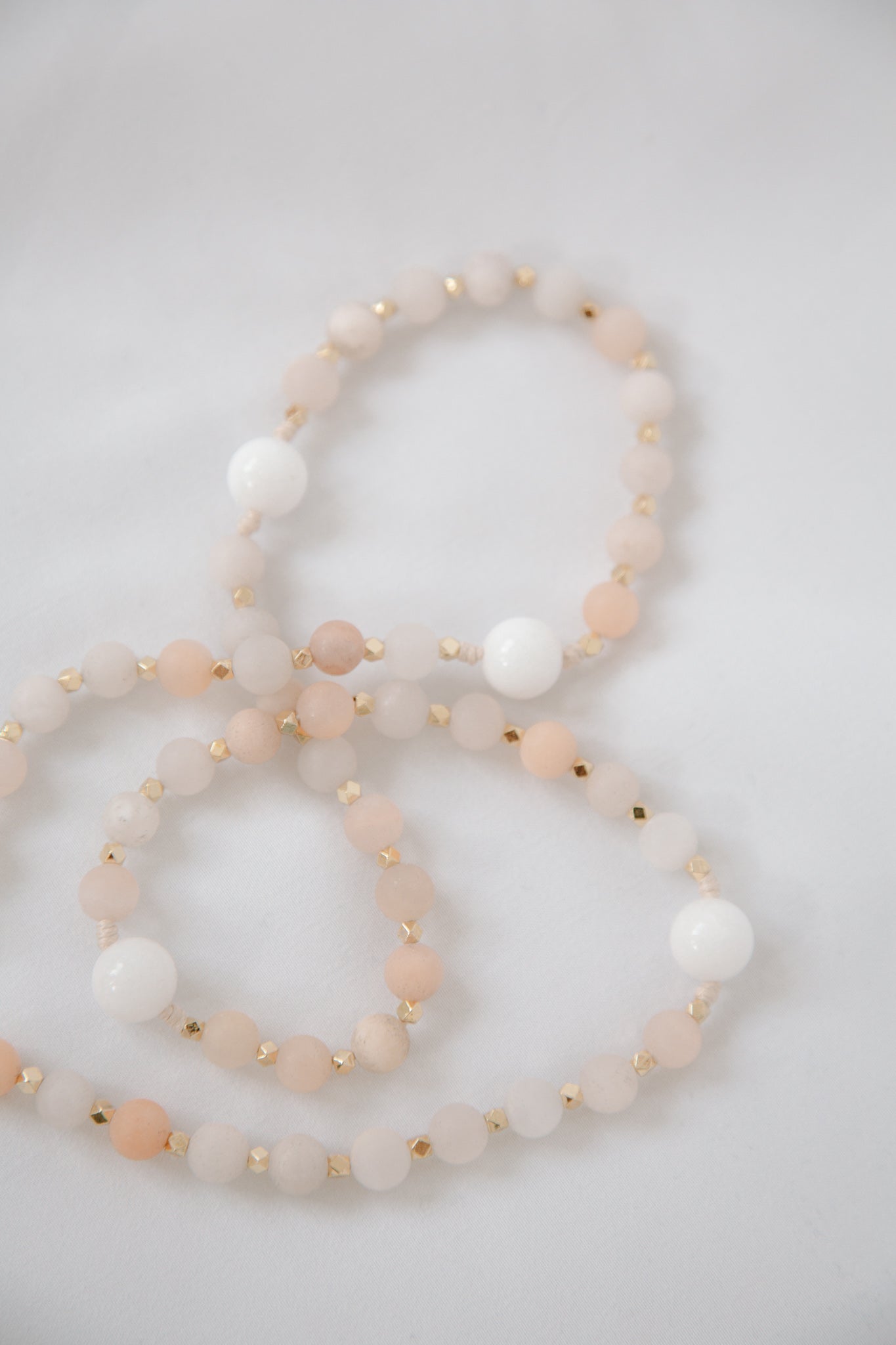 Pink and white immaculate heart rosary beads on white background