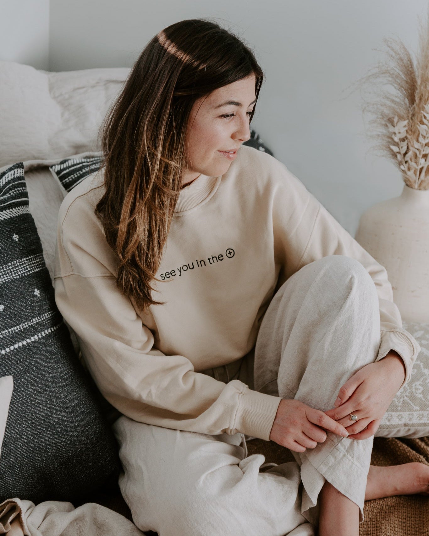 Woman wearing a beige sweater on a couch